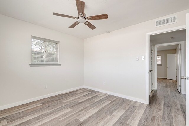 spare room featuring baseboards, ceiling fan, visible vents, and light wood-style flooring