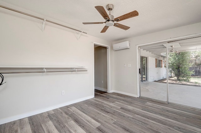 interior space with baseboards, ceiling fan, wood finished floors, and a wall unit AC