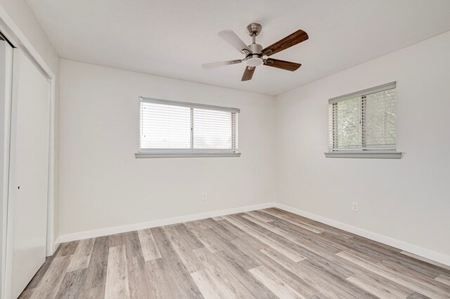 unfurnished bedroom featuring light wood-style floors, baseboards, and a closet