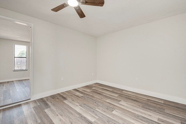 empty room featuring baseboards, ceiling fan, and light wood-style flooring