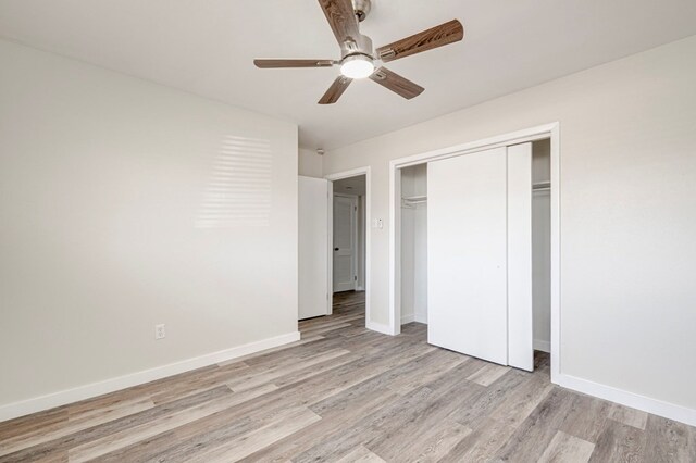 unfurnished bedroom with light wood-style floors, baseboards, ceiling fan, and a closet