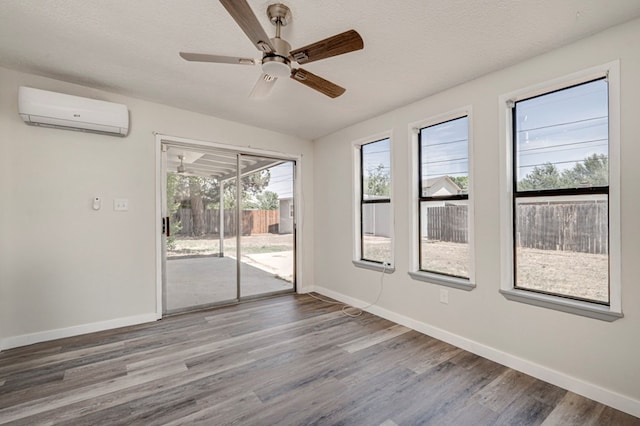 spare room with baseboards, a wall mounted air conditioner, a ceiling fan, and wood finished floors
