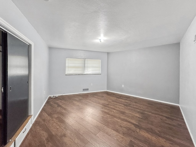 spare room with dark hardwood / wood-style floors and a textured ceiling