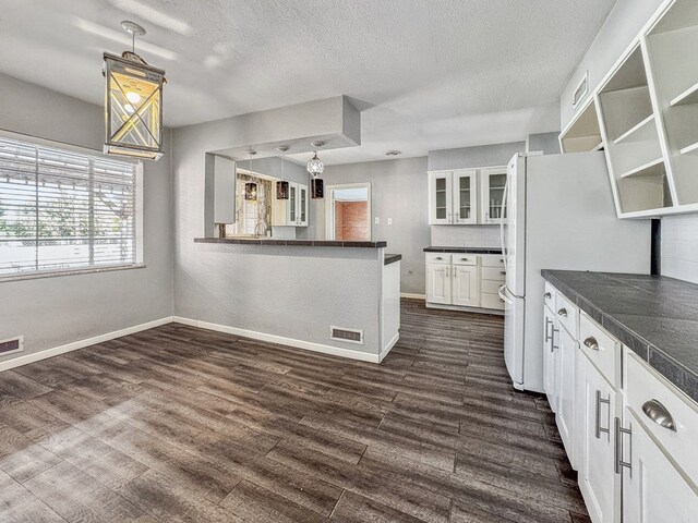 kitchen featuring dark wood-type flooring, a textured ceiling, white refrigerator, pendant lighting, and white cabinets