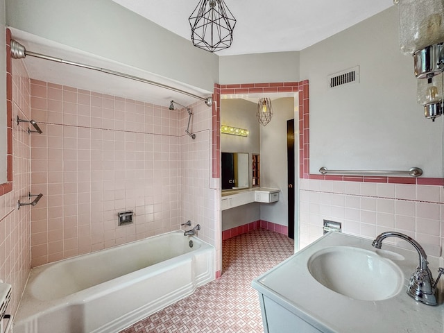 bathroom featuring tile walls, vanity, and tiled shower / bath