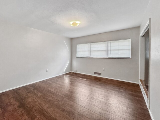 spare room featuring dark hardwood / wood-style floors and a textured ceiling