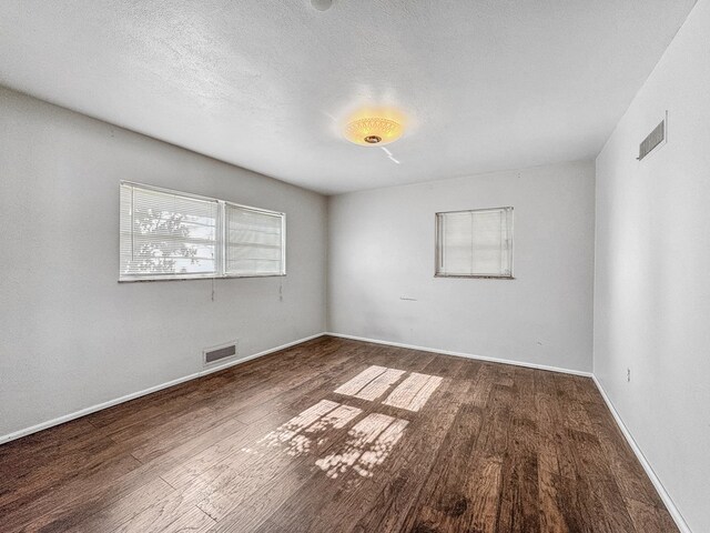 unfurnished room featuring dark hardwood / wood-style floors and a textured ceiling