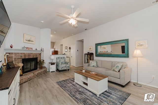 living room featuring a brick fireplace, baseboards, ceiling fan, and light wood finished floors