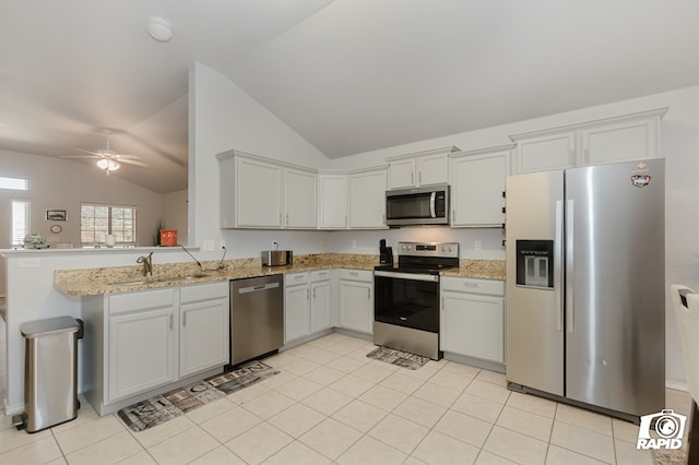 kitchen with stainless steel appliances, light stone counters, a peninsula, and a sink