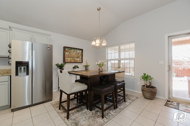 dining space featuring lofted ceiling, light tile patterned flooring, baseboards, and a notable chandelier