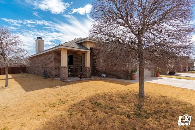 view of front of home with brick siding, a chimney, concrete driveway, fence, and a front lawn