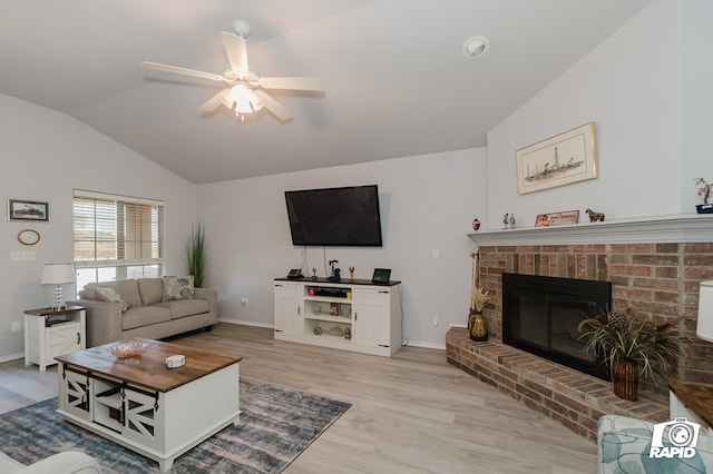 living room with ceiling fan, baseboards, vaulted ceiling, light wood-style floors, and a brick fireplace