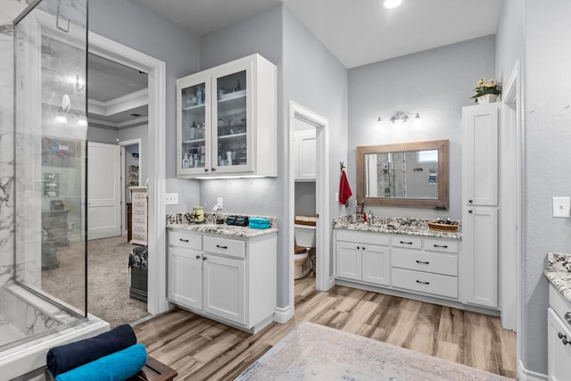 6811 Elkins Rd, Midland, TX 79705 - full bathroom with a shower stall, two vanities, and wood finished floors