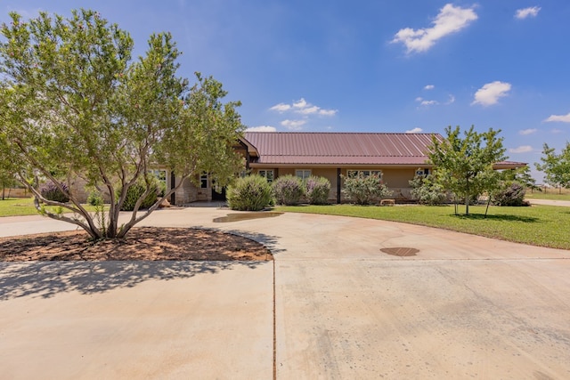 6811 Elkins Rd, Midland, TX 79705 - view of front of property featuring curved driveway, a front lawn, stucco siding, and a metal roof