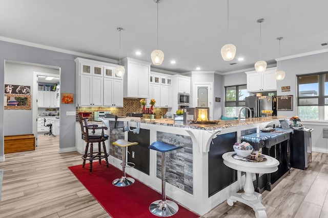 6811 Elkins Rd, Midland, TX 79705 - kitchen with stainless steel appliances, a kitchen bar, recessed lighting, decorative backsplash, and white cabinetry