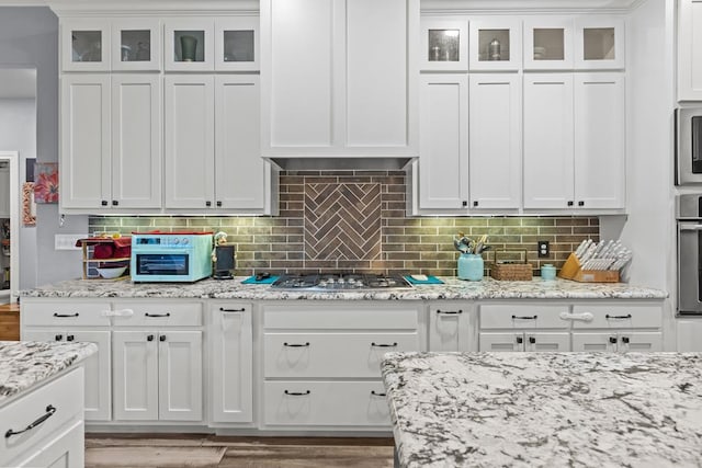 6811 Elkins Rd, Midland, TX 79705 - kitchen with white cabinetry, glass insert cabinets, stainless steel appliances, and decorative backsplash