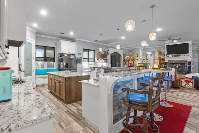 6811 Elkins Rd, Midland, TX 79705 - kitchen with ornamental molding, a large island, stainless steel fridge, a fireplace, and open floor plan