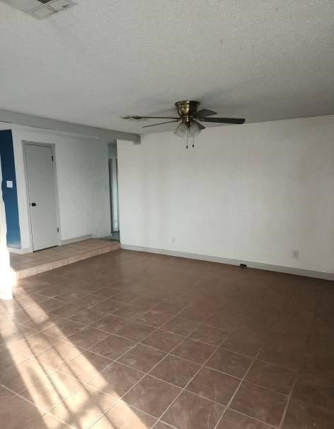 tiled spare room with ceiling fan and a textured ceiling