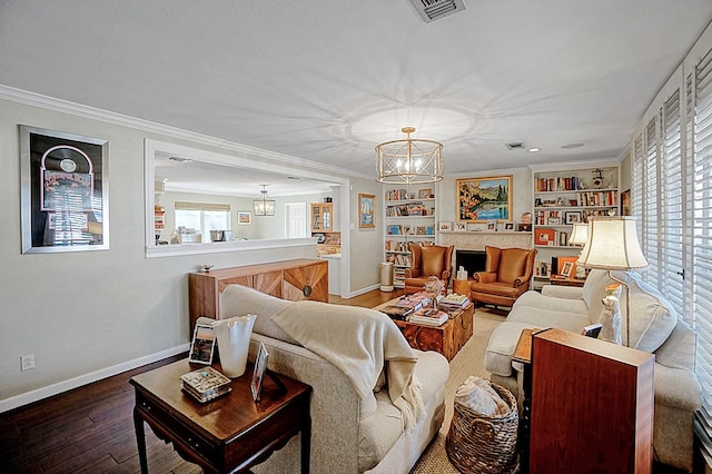 living room featuring an inviting chandelier, hardwood / wood-style flooring, ornamental molding, and built in shelves