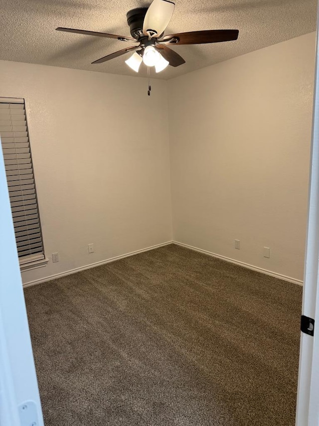 empty room featuring a ceiling fan, baseboards, dark carpet, and a textured ceiling