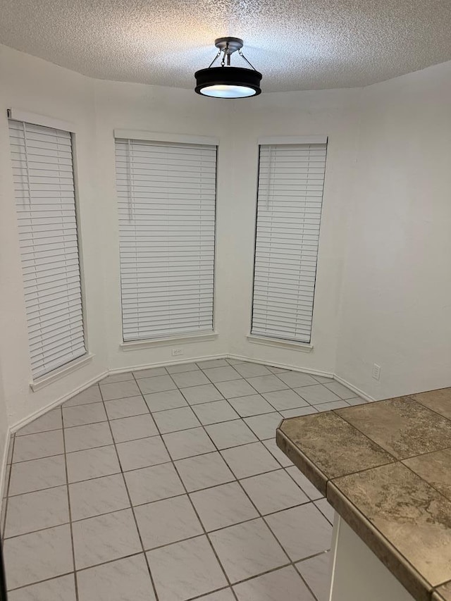 unfurnished dining area featuring light tile patterned floors and a textured ceiling