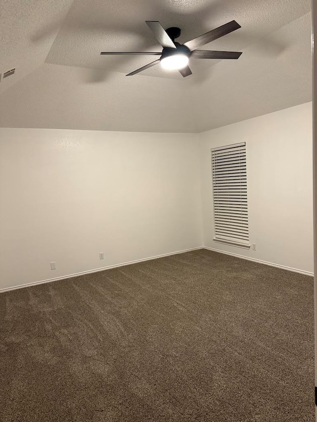 spare room with visible vents, a textured ceiling, a ceiling fan, and dark colored carpet