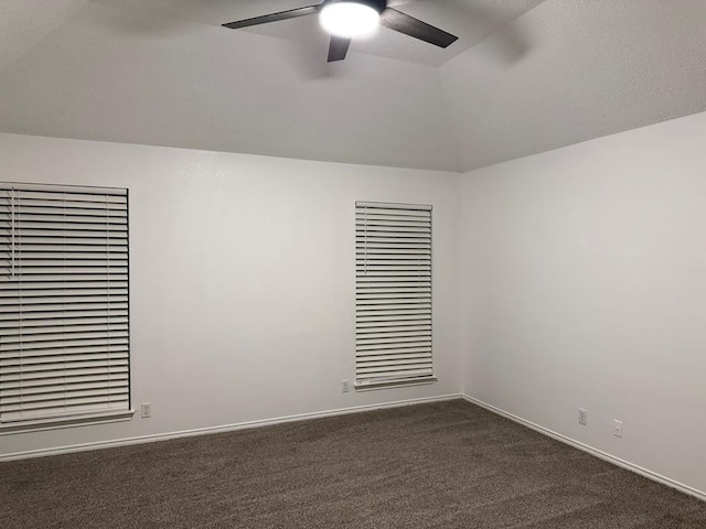 spare room with dark colored carpet, baseboards, a ceiling fan, and vaulted ceiling