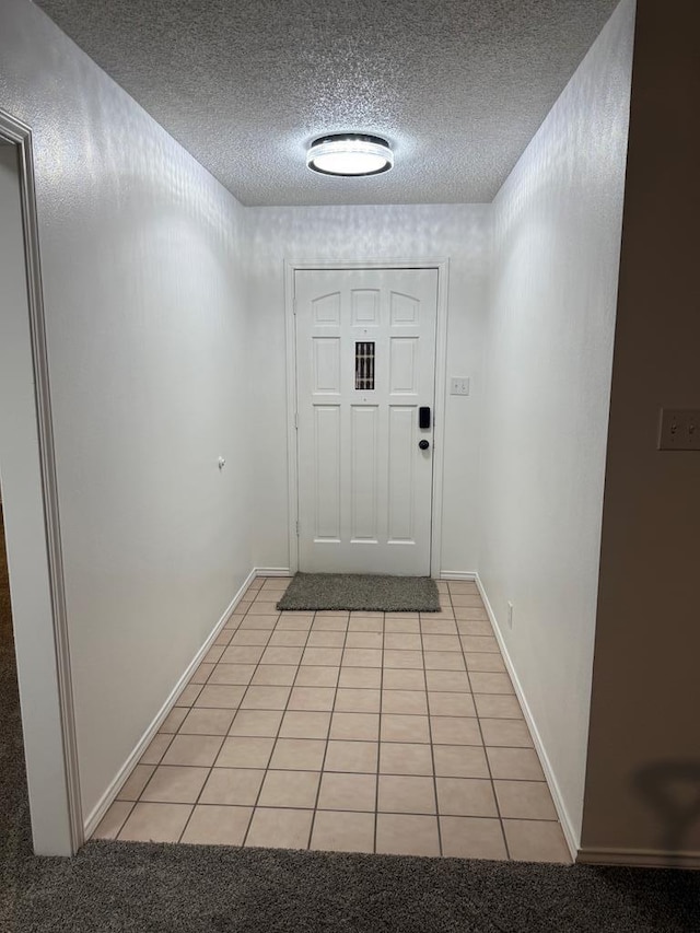 entryway with light tile patterned flooring, a textured ceiling, and baseboards