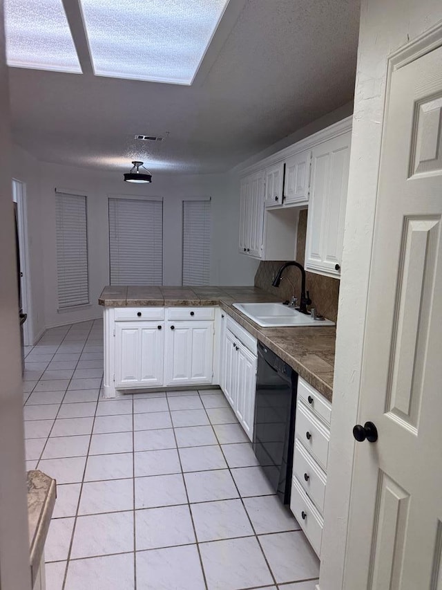 kitchen with a sink, white cabinetry, a peninsula, light tile patterned floors, and dishwasher