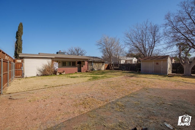 rear view of property with a fenced backyard, an outdoor structure, brick siding, and a storage unit