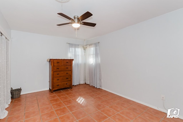 empty room featuring baseboards, a ceiling fan, and light tile patterned flooring