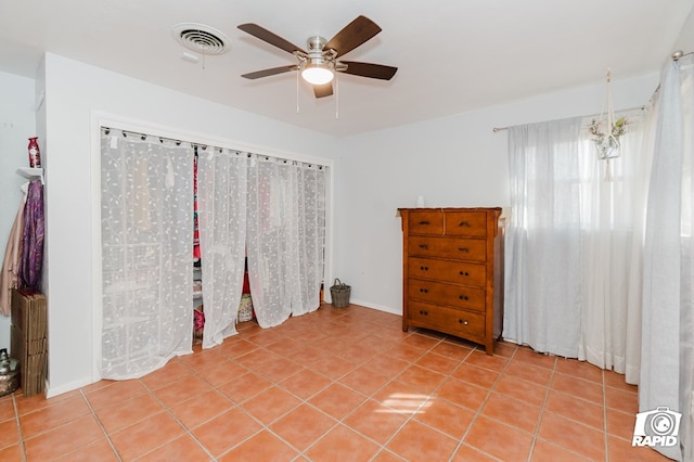 tiled spare room with ceiling fan, visible vents, and baseboards