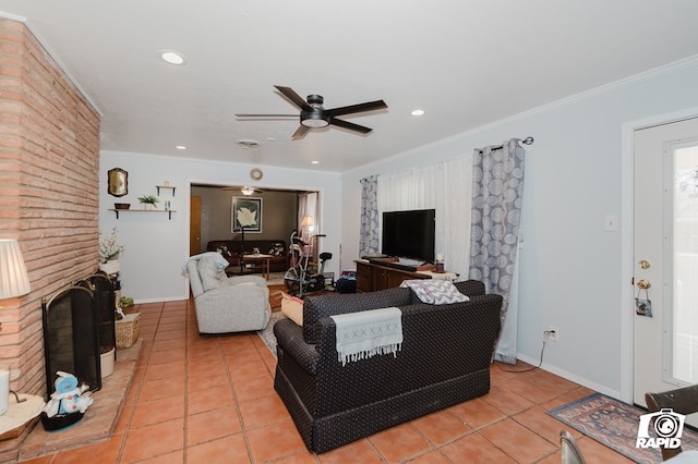 living room featuring a brick fireplace, light tile patterned floors, a ceiling fan, and crown molding