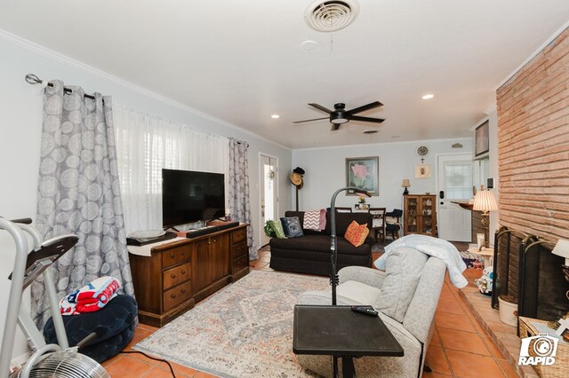 living area featuring light tile patterned floors, visible vents, ornamental molding, a brick fireplace, and recessed lighting