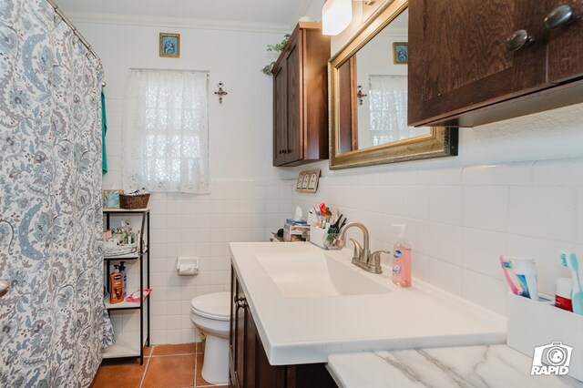 bathroom with tile patterned flooring, toilet, vanity, tile walls, and ornamental molding