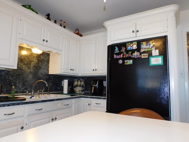 kitchen with white cabinetry, decorative backsplash, and freestanding refrigerator