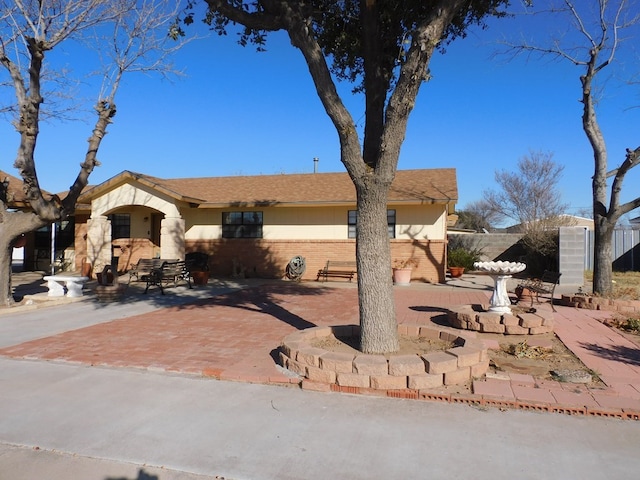 ranch-style house featuring a patio area, fence, and brick siding