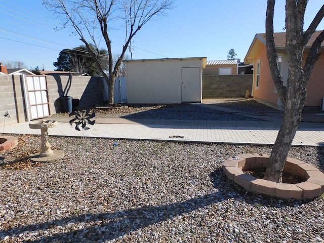 view of yard with an outbuilding, a shed, a patio area, and a fenced backyard