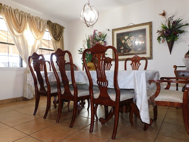 dining space with a chandelier, tile patterned floors, and baseboards