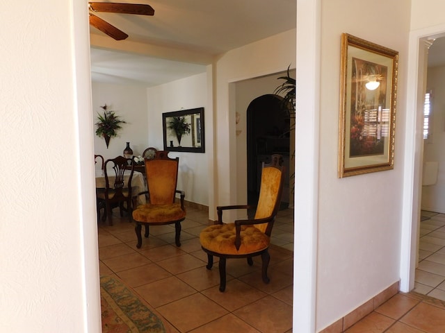 sitting room with arched walkways, light tile patterned flooring, ceiling fan, and baseboards