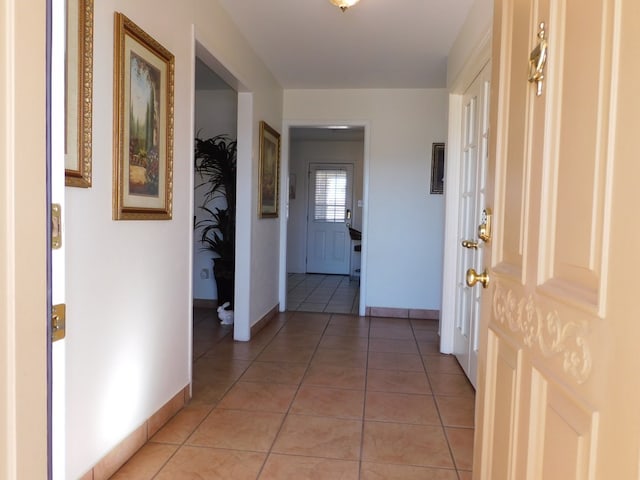 hallway with light tile patterned floors and baseboards