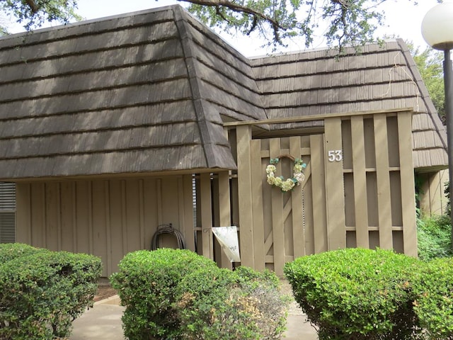 view of home's exterior featuring board and batten siding and mansard roof