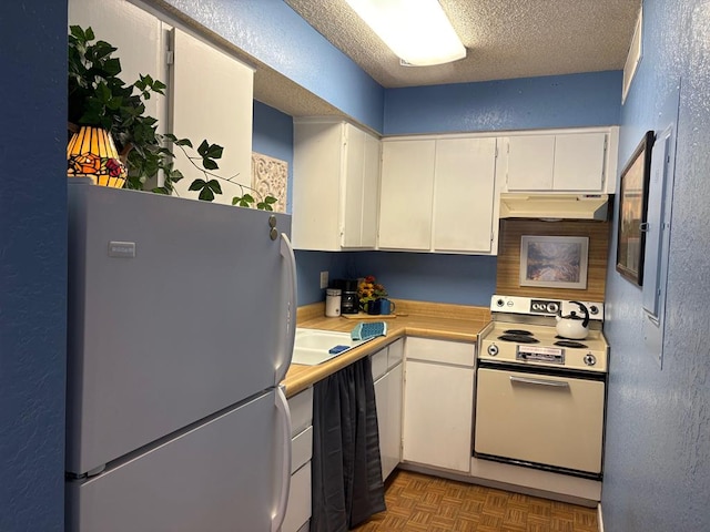 kitchen featuring freestanding refrigerator, range with electric stovetop, light countertops, white cabinetry, and under cabinet range hood
