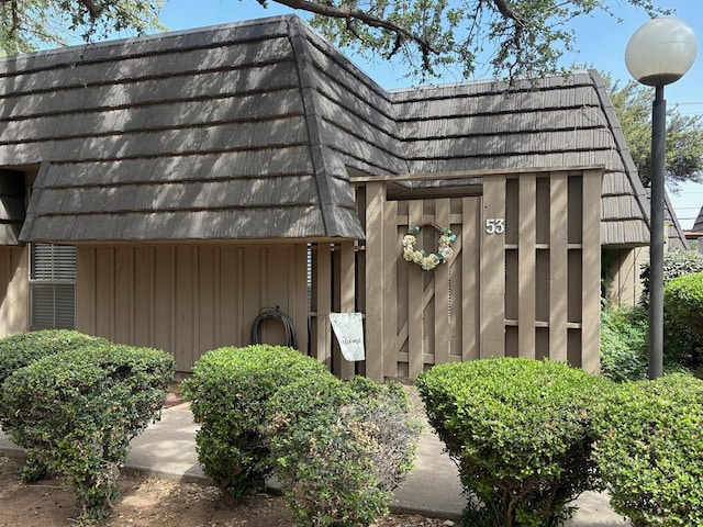 view of side of home featuring board and batten siding and mansard roof