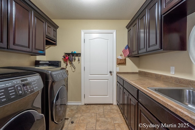 clothes washing area with cabinet space, washer and dryer, stone finish floors, baseboards, and a textured ceiling