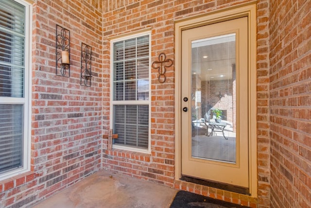 view of exterior entry featuring brick siding