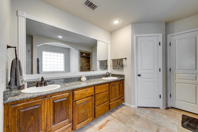 full bathroom with double vanity, visible vents, a sink, and tiled shower