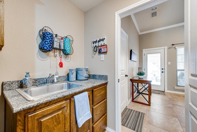 kitchen with a sink, visible vents, light countertops, ornamental molding, and brown cabinetry