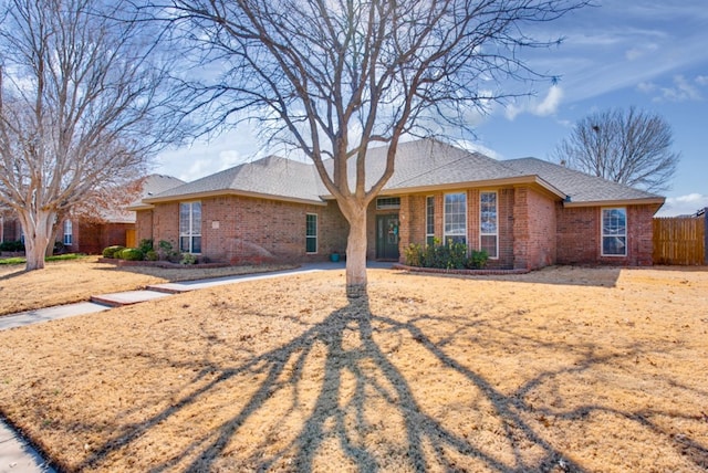 ranch-style home featuring fence and brick siding