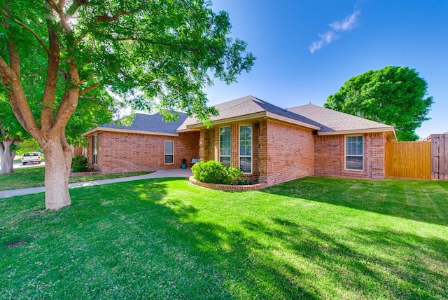 single story home with roof with shingles, fence, brick siding, and a front yard